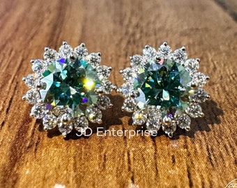 May include: A pair of silver earrings featuring a large, round, green gemstone encircled by smaller, clear gemstones. The earrings are set in a flower-shaped design.