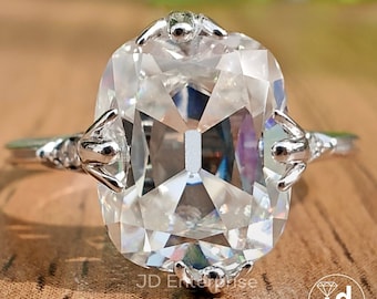 May include: A silver ring with a large, clear, cushion-cut gemstone. The setting features intricate, claw-like prongs.