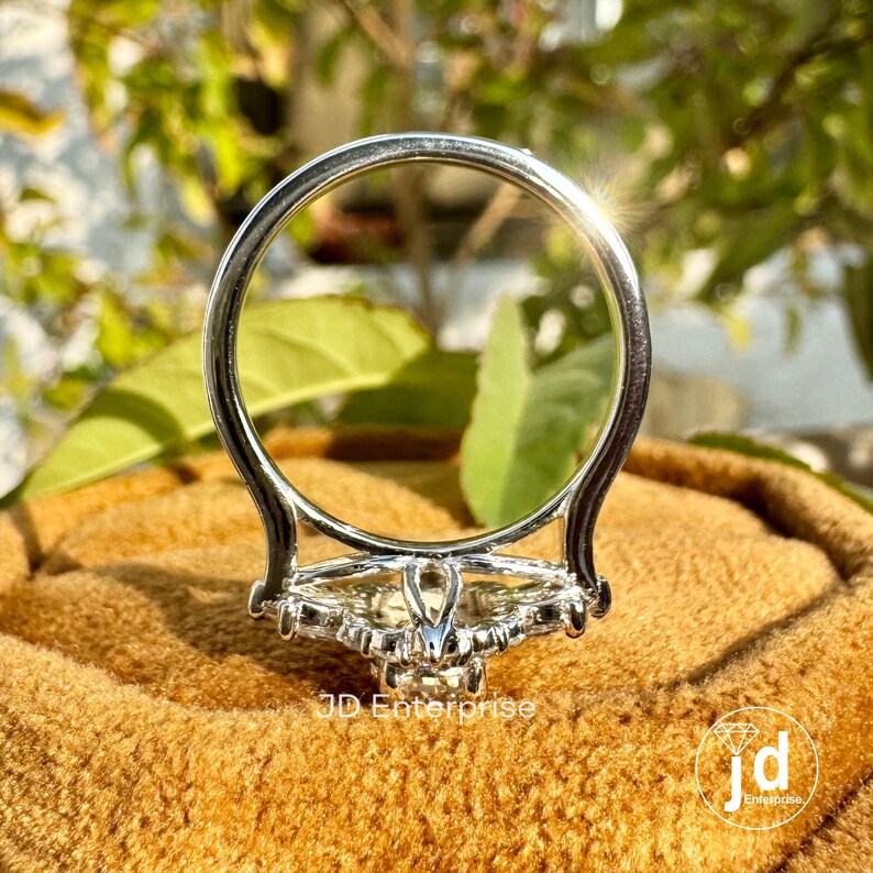 May include: A silver ring with a large, clear center stone surrounded by smaller stones. The ring is on a brown velvet box.