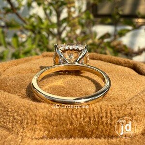 May include: A gold engagement ring with a large, round, clear center stone surrounded by smaller diamonds. The ring is on a brown velvet surface.