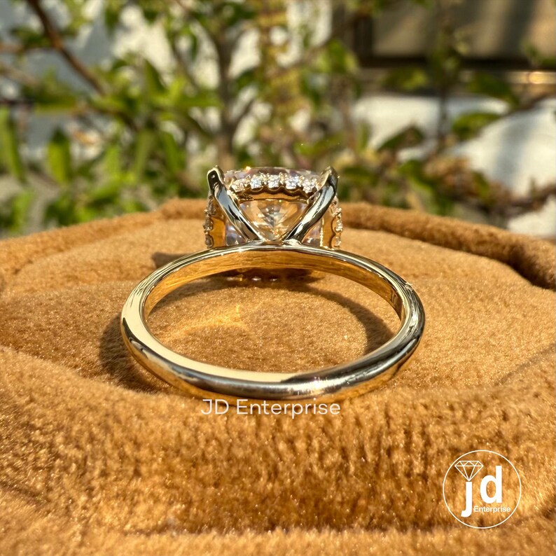 May include: A gold engagement ring with a large, round, clear center stone surrounded by smaller diamonds. The ring is on a brown velvet surface.