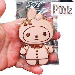 May include: A pink and gold-toned character pin in a clear plastic package. The pin features a cartoon bunny with a flower on its ear and the word "Pink" in a pink font.