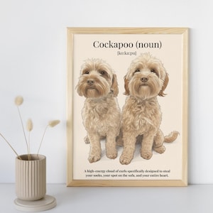 May include: A framed print featuring two Cockapoo dogs with light brown fur. The print includes the word "Cockapoo" and a definition. The bottom of the print reads, "A high-energy cloud of curls specifically designed to steal your socks, your spot on the sofa, and your entire heart."