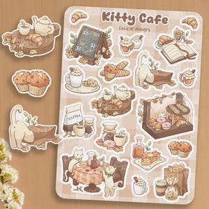 May include: A sticker sheet with a "Kitty Cafe" theme, showcasing illustrations of cats, pastries, coffee, and a menu board. The stickers use a warm colour palette of browns, beiges, and creams. The text "Kitty Cafe" is visible.