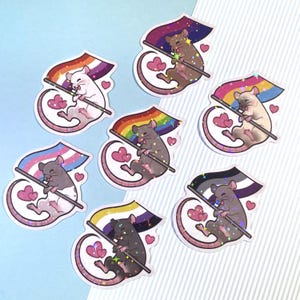 Puede incluir: Seis pegatinas de ratas coloridas con detalles de purpurina. Cada rata sostiene una bandera del orgullo, incluidas las banderas del arcoíris, transgénero, bisexual, pansexual, asexual y lesbiana.