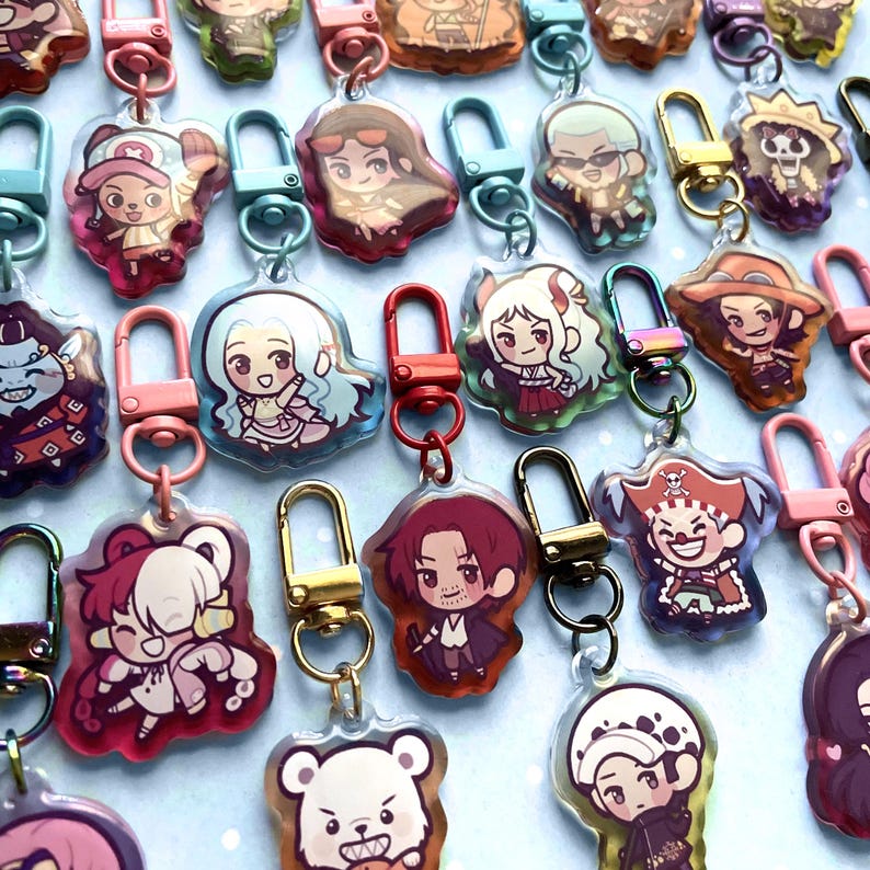 May include: A collection of colorful acrylic keychains featuring various anime characters. Each keychain has a unique design with vibrant colors and attached to a metal clasp. The keychains are in various shapes and sizes.