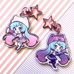 Può includere: Due ciondoli in acrilico in stile anime. Ogni ciondolo presenta un personaggio con i capelli blu, che tiene in mano un megafono. I ciondoli hanno capelli sfumati rosa e viola, indossando abiti con accenti rosa e viola. Ogni ciondolo ha una chiusura a forma di stella.