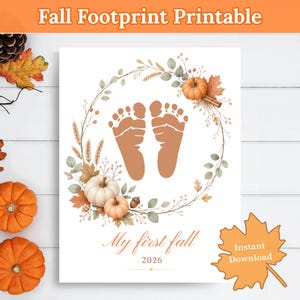 May include: A printable wall art design featuring a pair of brown baby footprints centered within a wreath of autumn leaves, wheat, and pumpkins. The text reads My first fall 2026. The design is set against a white background with fall decor.
