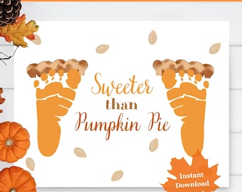 May include: A white printable featuring orange footprint art, resembling pumpkin pie slices, with the text "Sweeter than Pumpkin Pie." The design includes scattered seed illustrations and a fall leaf graphic with "Instant Download" text.