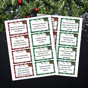 K&ouml;nnte beinhalten: Ein Satz von 12 Weihnachts-Spielkarten mit gr&uuml;nem und rotem kariertem Hintergrund und Schneeflocken. Jede Karte hat eine andere Herausforderung, die w&auml;hrend eines Geschenketauschspiels zu bew&auml;ltigen ist. Die Karten tragen den Text "Wrap Trap" auf sich.