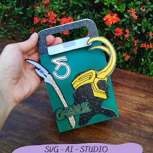 May include: A green cardstock party favor box with a gold glitter Loki silhouette, a gold glitter "Charlie" name tag, a gold glitter horn, and a white number "5" on the front.