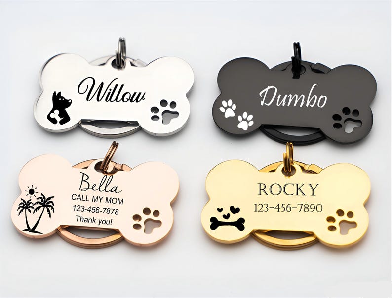 Puede incluir: Cuatro etiquetas de identificaci&oacute;n para mascotas en forma de hueso en plata, negro, oro rosa y oro. Cada etiqueta presenta un nombre, huellas de patas y otros gr&aacute;ficos. Una etiqueta dice "Willow" con una silueta de perro. Otra dice "Bella".