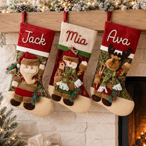 Può includere: Tre calze natalizie con i nomi ricamati Jack, Mia e Ava. Ogni calza presenta un personaggio di peluche: Babbo Natale, un pupazzo di neve e una renna. Le calze hanno risvolti rossi, corpi verdi a fantasia e punte color beige.