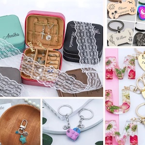 May include: Assortment of personalized jewelry and keychains.  A teal jewelry box with the name Annika engraved on it. A pink jewelry box with the name Elliot engraved on it. A black jewelry box with the name Manuela engraved on it. A silver keychain with a heart charm and a lego charm. A gold keychain with a heart charm and the words "I love you" engraved on it. A gold keychain with a heart charm and the words "Thank you for being part of my story" engraved on it. A gold keychain with a heart charm and the words "Drive safe I love you!" engraved on it. A pink, clear resin keychain with a letter M and flowers inside. A black, clear resin keychain with a letter M and flowers inside. A white, clear resin keychain with a letter M and flowers inside. A silver dog tag with the name Oliver engraved on it. A rainbow dog tag with the name Rocky engraved on it. A black dog tag with the name Barnaby engraved on it. A silver dog tag with the name Willow engraved on it.