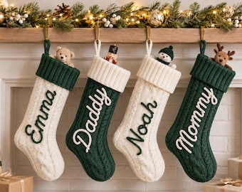 May include: Four cable-knit Christmas stockings hanging in a row, alternating between cream and dark green colors. Each stocking features a contrasting embroidered name: Emma, Daddy, Noah, and Mommy. Small plush toys peek out from the top cuffs.