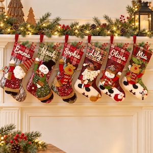 May include: Six Christmas stockings hanging in a row, each featuring a unique plush character like Santa, a snowman, or a reindeer. The stockings are decorated with plaid patterns, red and green fabrics, and white cuffs, with names Emma, Noah, Sophie, Lily, Olivia, and Mia.
