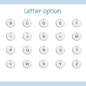 May include: A set of 26 white round metal tags with black letters, each letter of the alphabet is represented.