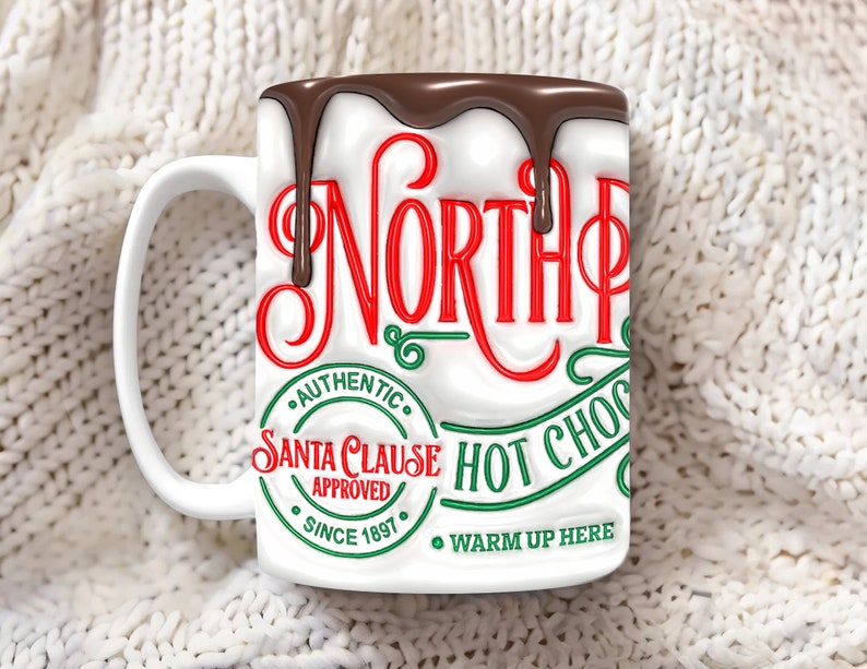 K&ouml;nnte beinhalten: Wei&szlig;e Keramiktasse mit einem roten und gr&uuml;nen Design, auf dem "North Pole Authentic Santa Clause Approved Since 1897 Warm Up Here" steht, mit einem schokoladenartigen &Uuml;berzug, der an der Seite heruntertropft.