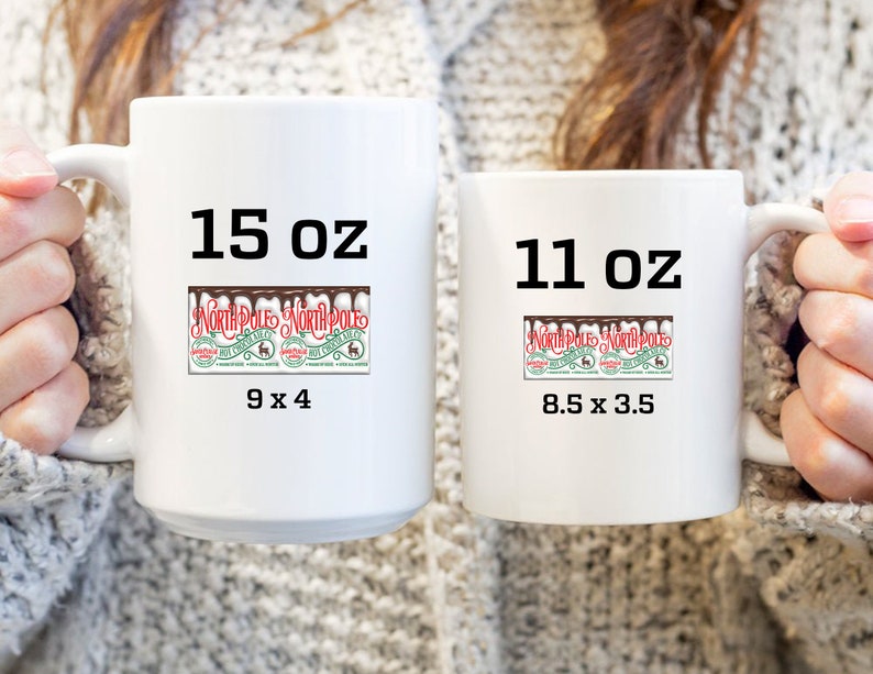 K&ouml;nnte beinhalten: Zwei wei&szlig;e Keramikbecher mit schwarzem Text und einer Grafik eines Nordpol-Hei&szlig;schokoladen-Etiketts. Der gr&ouml;&szlig;ere Becher ist 15 oz gro&szlig; und misst 9 x 4 Zoll. Der kleinere Becher ist 11 oz gro&szlig; und misst 8,5 x 3,5 Zoll.