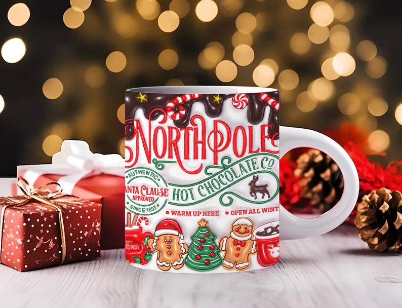 K&ouml;nnte beinhalten: Eine wei&szlig;e Keramiktasse mit einem festlichen Design mit den Worten "North Pole Hot Chocolate Co." und einem Lebkuchenmann, einem Weihnachtsbaum und einem Rentier. Die Tasse hat einen wei&szlig;en Henkel und ist mit einer braunen Fl&uuml;ssigkeit gef&uuml;llt.