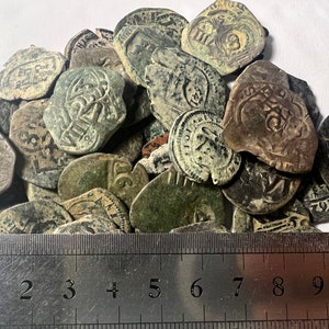 Peut inclure: Une collection de vieilles pièces d'argent ternies avec une règle pour l'échelle. Les pièces sont principalement rondes, mais certaines sont octogonales. Les pièces sont de tailles différentes et présentent divers motifs.
