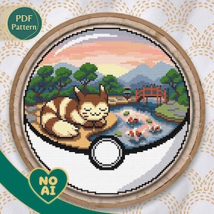 May include: Cross-stitch pattern of a cat in a Japanese garden scene, framed in a wooden hoop. The design features a cat, a pond with koi fish, a red bridge, and trees, all within a stylized Pokeball. Text on the image reads "PDF Pattern" and "NO AI".