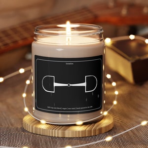 May include: A brown soy wax candle with a black label and a white illustration of a horse bit. The label reads "lunaelux" and "100% soy wax blend | vegan | non-toxic | hand-poured in the USA".