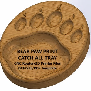 Puede incluir: Bandeja de madera con forma de huella de pata de oso. La bandeja tiene un centro profundo y cuatro huellas de patas alrededor del borde. El texto "BEAR PAW PRINT CATCH ALL TRAY" está impreso en la bandeja. El texto "CNC Router/3D Printer Files DXF/STL/PDF Template" también está impreso en la bandeja.