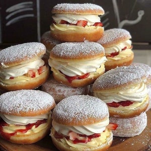 Peut inclure: Une pile de beignets fourrés à la crème, à la confiture de fraises et au sucre glace. Les beignets sont disposés en forme de pyramide.