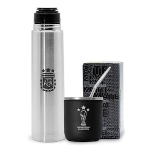 Puede incluir: Un termo plateado con el logo de la AFA y una mate negra con el logo de la selección argentina y una bombilla plateada. La mate está en una caja con la palabra "mate" repetida en blanco y negro.