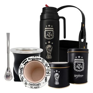 Puede incluir: Un set de mate negro que incluye un termo con el logo de la AFA y la copa del mundo, una bombilla de metal, un mate con el texto 'Argentina Campeones del Mundo' y dos latas negras con la marca AFA y una correa de transporte de cuero.