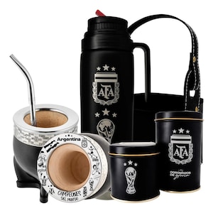 Puede incluir: Un juego de yerba mate negro con temática argentina. El juego incluye un mate con una bombilla de metal, un termo, dos latas y una bolsa de transporte negra. Los artículos presentan el logotipo de la Asociación Argentina de Fútbol y el trofeo de la Copa Mundial de la FIFA.