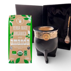 Può includere: Un set di yerba mate con una zucca nera con bordo argentato e design a sole, una cannuccia di metallo e un sacchetto di yerba mate "amanda". La borsa è verde e marrone con testo in spagnolo e inglese. Il set è presentato in una scatola nera.