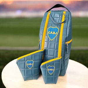 Puede incluir: Una taza de cerámica blanca con asa negra y el texto "But First, Coffee" en negrita negra. La taza se encuentra sobre un fondo borroso, sugiriendo un ambiente acogedor.