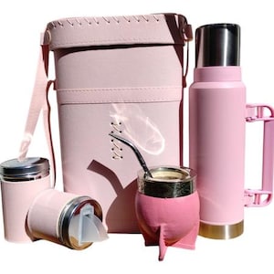 Könnte beinhalten: Ein rosa Yerba Mate Set mit Thermoskanne, Tragetasche, zwei Behältern und einer Mate-Tasse mit Bombilla. Das Set besteht aus rosa Materialien mit silbernen und goldenen Akzenten. Die Tragetasche hat einen Schulterriemen.