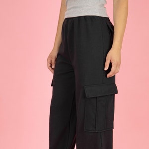 May include: Black cargo pants with a large pocket on the right leg. The pants are made of a soft, comfortable fabric and have a relaxed fit.
