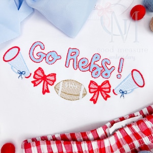 May include: White embroidered onesie with the text "Go Rebs!" in blue and red lettering. The onesie also features a football, two red bows, and two blue megaphones.