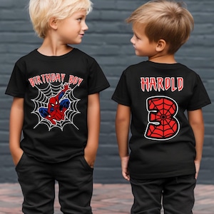 May include: Two black t-shirts with a Spiderman theme. One shirt says "Birthday Boy" with a Spiderman graphic and the other shirt says "Harold" with the number 3 in a Spiderman web design.