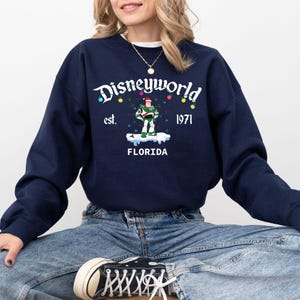 May include: Navy blue sweatshirt with a "Disneyworld" graphic. The design includes the text "est. 1971" and a cartoon character. The word "FLORIDA" is also included in the design.
