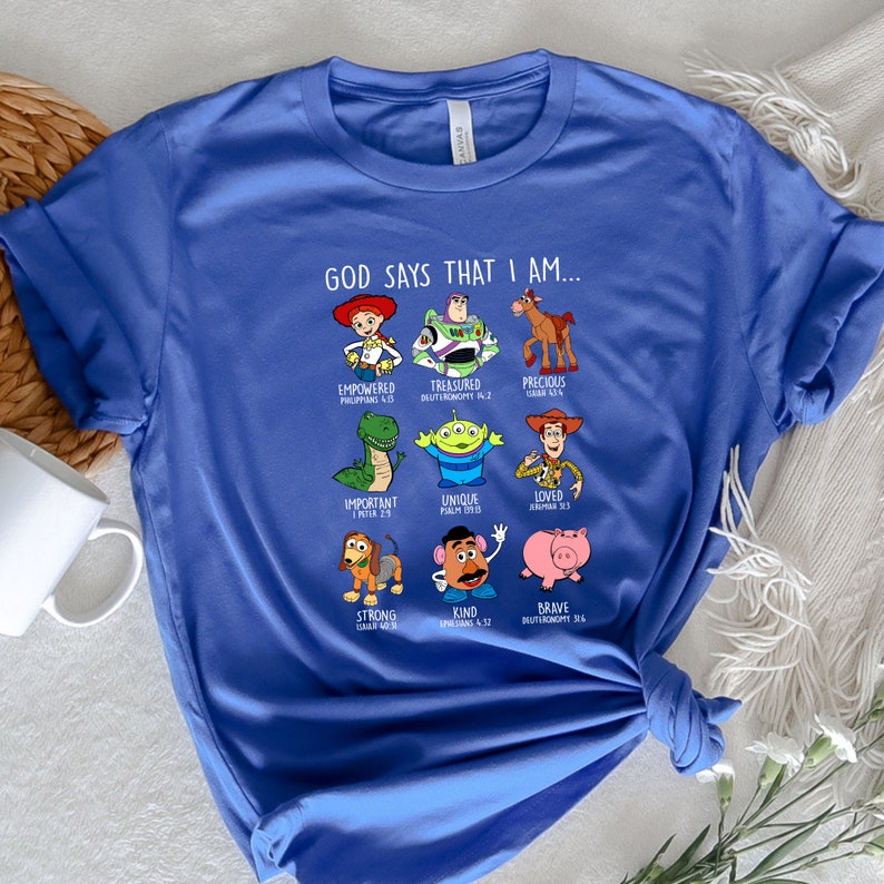 Peut inclure: Un t-shirt bleu avec un graphique de personnages de Toy Story et le texte "Dieu dit que je suis..." avec des versets bibliques list&eacute;s sous chaque personnage.