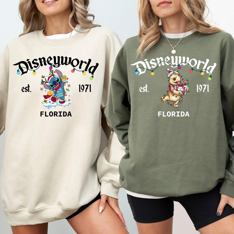 May include: Two sweatshirts with the text "Disneyworld" and "Florida" printed on them. One is beige with a Stitch graphic, the other is olive green with a Winnie the Pooh graphic. Both have "est. 1971" printed on them.