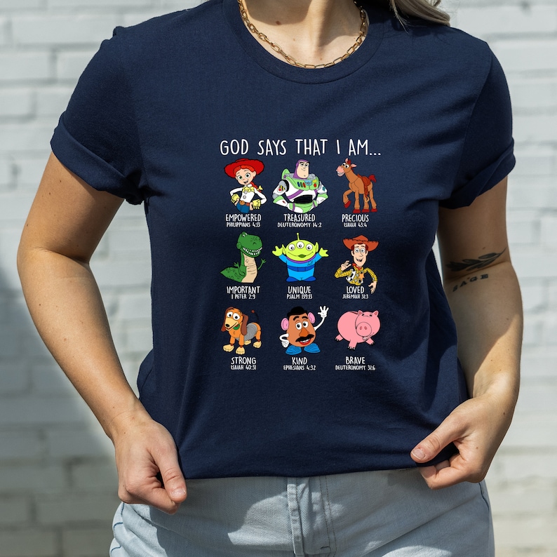 Peut inclure: Un t-shirt bleu marine avec un motif de personnages de Toy Story et des citations inspirantes. Le texte dit "Dieu dit que je suis..." et liste des mots comme "puissant", "pr&eacute;cieux", "important", "unique", "aim&eacute;", "fort", "gentil" et "courageux" avec des versets bibliques correspondants.
