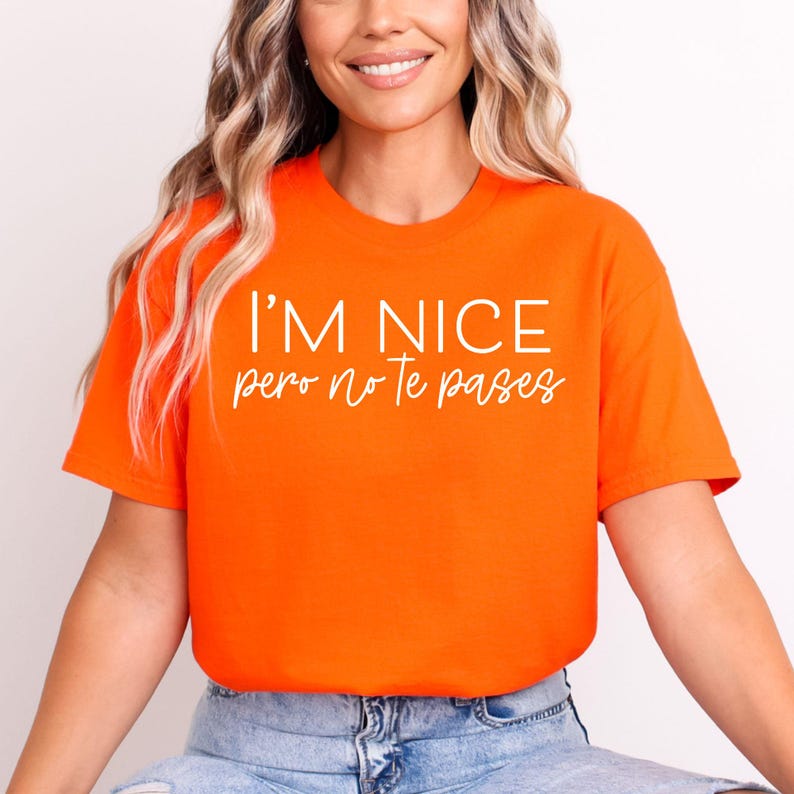 May include: A bright orange short-sleeved t-shirt featuring the text I'M NICE in a bold, white sans-serif font, followed by the text pero no Te pases in a white, cursive script font centered on the chest of the garment.