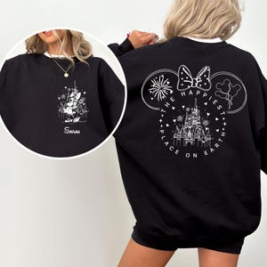 May include: Black sweatshirt with white trim featuring a Disney castle and Minnie Mouse design. The front has a castle and Minnie Mouse graphic with the name "Sarah". The back has a Mickey Mouse head outline with the text "The Happiest Place on Earth".