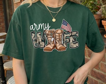 Peut inclure: Un t-shirt à manches courtes vert foncé avec une impression graphique comportant le mot army en écriture blanche, une paire de bottes de combat beige avec des lettres à motif camouflage et un petit drapeau américain avec des plaques d'identité.