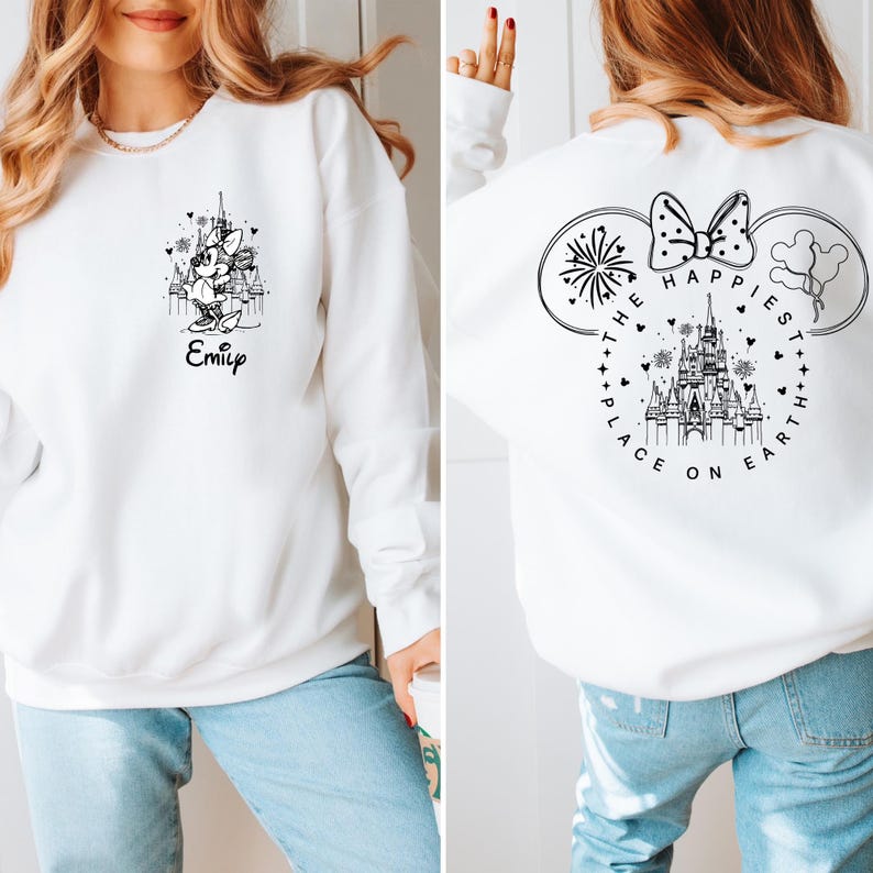 May include: White sweatshirt featuring a black and white Minnie Mouse graphic with the name "Emily" below. The back of the sweatshirt displays a Mickey Mouse ear design with fireworks, balloons, and the text "The Happiest Place on Earth."