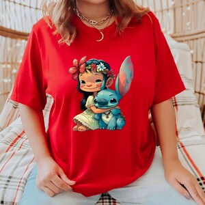 May include: Red t-shirt with a graphic print of a girl with a flower crown hugging a blue Stitch character from Lilo & Stitch.
