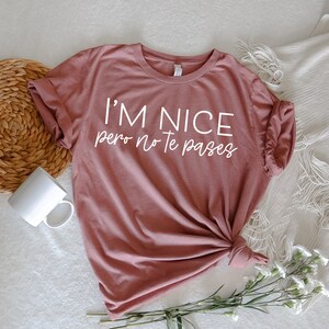 May include: A mauve t-shirt with the text "I'm nice pero no te pases" in white lettering.
