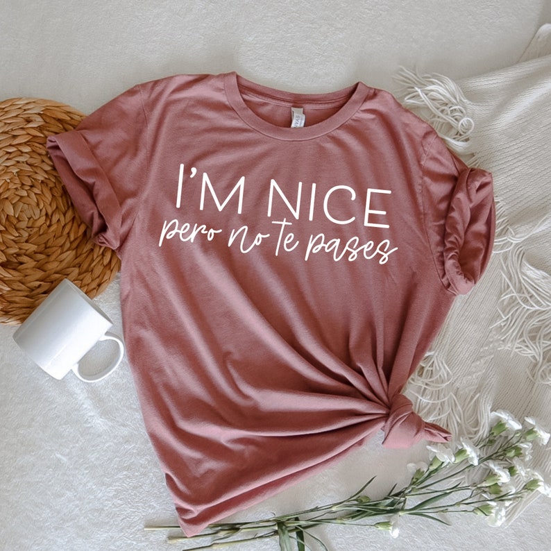 May include: A mauve t-shirt with the text "I'm nice pero no te pases" in white lettering.