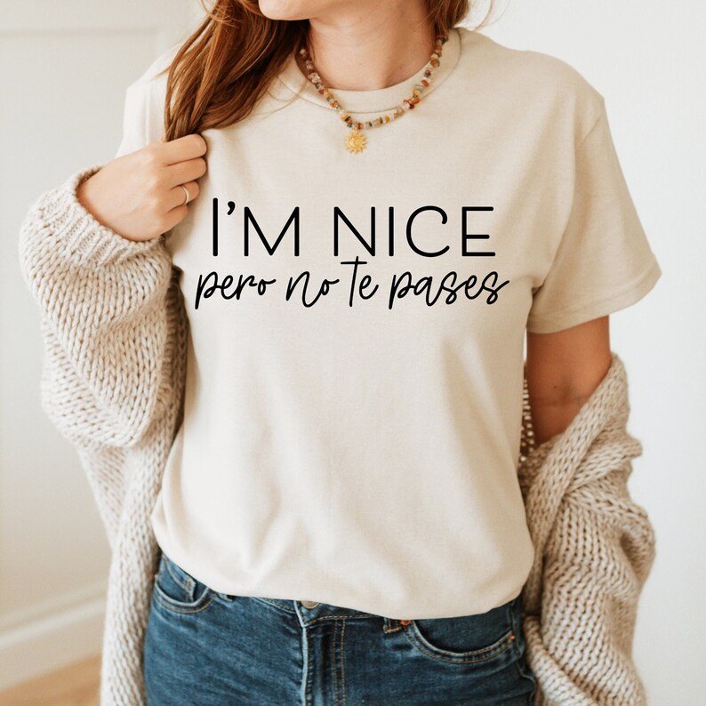 May include: A beige t-shirt with the text "I'm nice pero no te pases" printed in black.